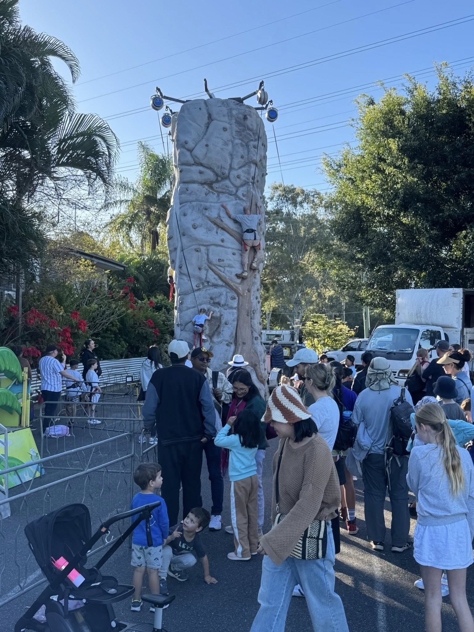 Kids climbing the rock wall with crowd watching